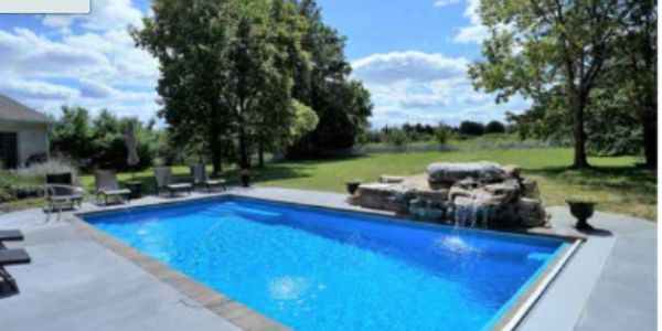 Outdoor rectangular pool with a waterfall feature and surrounding patio.