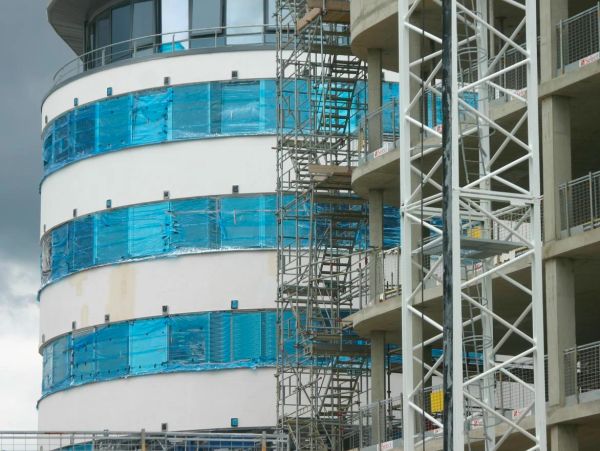 Building under construction with scaffolding and blue protective covering.