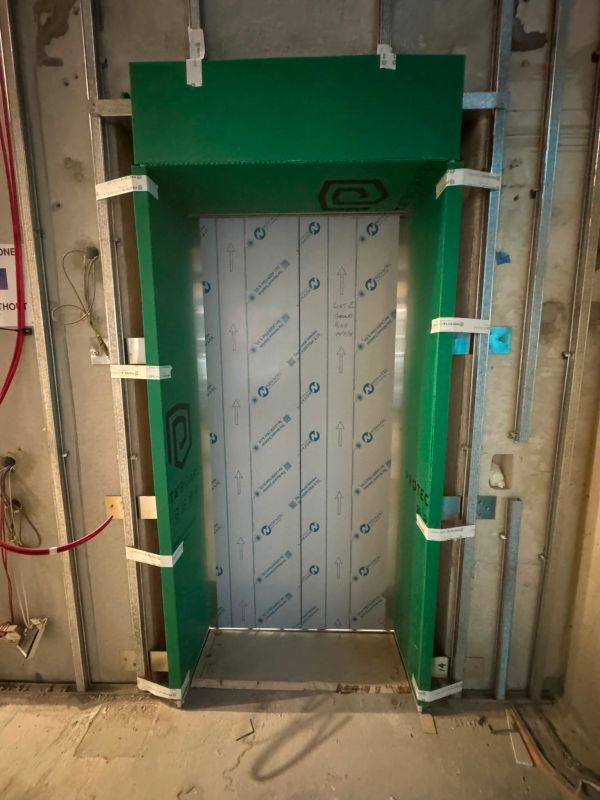 Elevator door under construction with green protective padding.