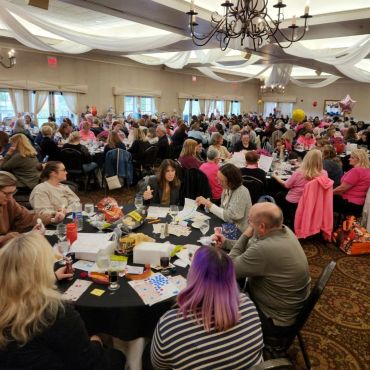 Crowded room with people playing bingo and socializing.