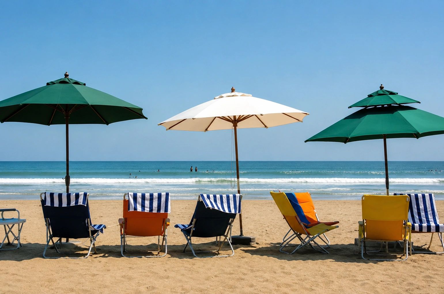Beach chairs with umbrellas facing the ocean on a sunny day.