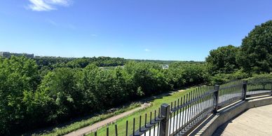 A scenic view of lush green trees and a clear blue sky from a balcony.