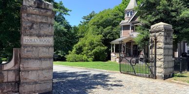 Stone entrance gate with 'Hollywood' sign leading to a Victorian-style house.