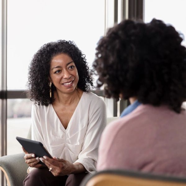 Two women engaged in a friendly conversation indoors.