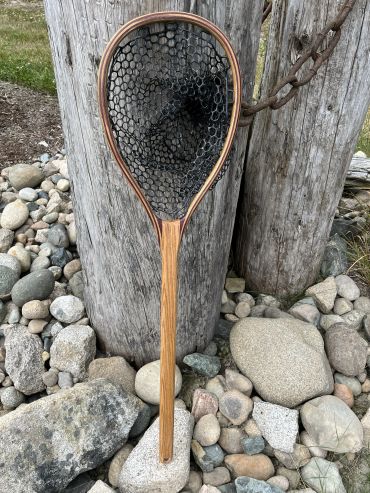 Wooden fishing net with a black mesh resting on stones.
