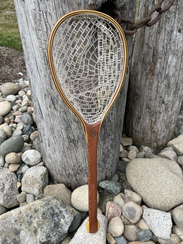 Wooden fishing net with mesh on stones.