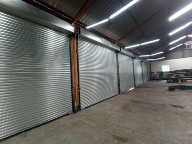 Metal rolling shutters inside a spacious industrial warehouse.