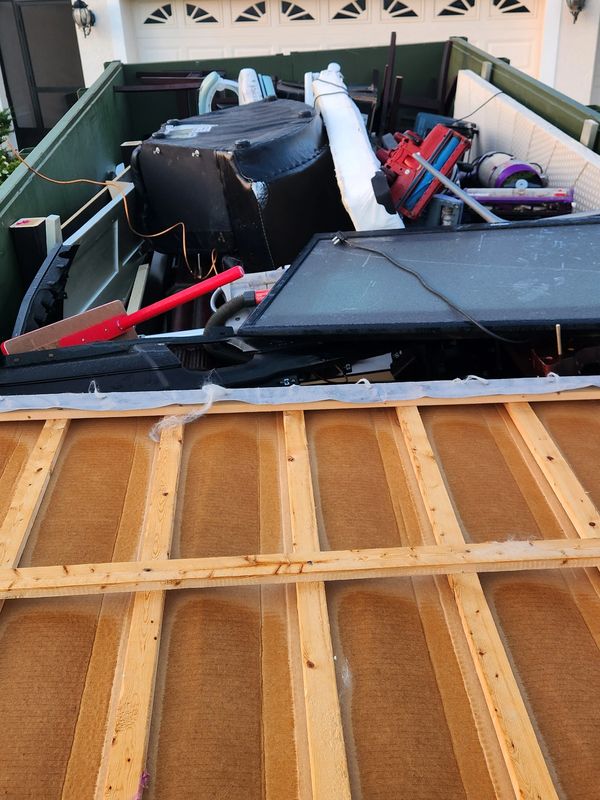 A dumpster filled with various discarded household items and furniture.