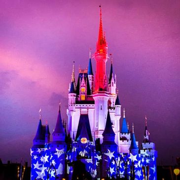 A brightly lit castle with star patterns against a purple sky at dusk.