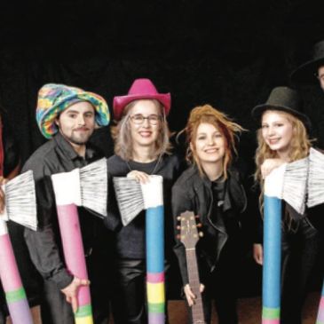Group of people in colorful hats holding oversized paintbrush props.
