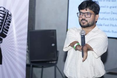 A man with a disability speaks into a microphone during a presentation.