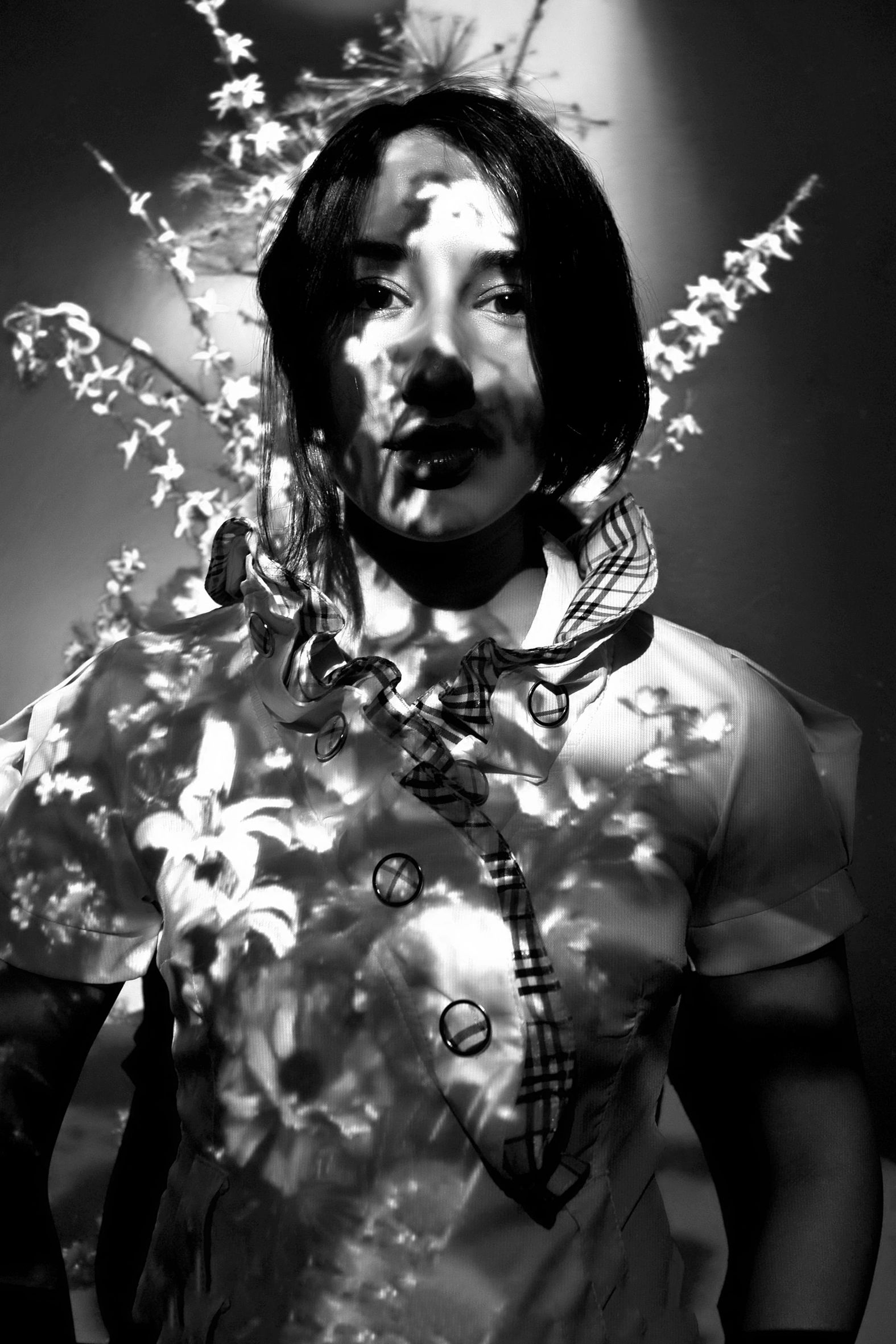Black-and-white portrait of a woman with floral shadows on her face and clothes. Artistic portrait p