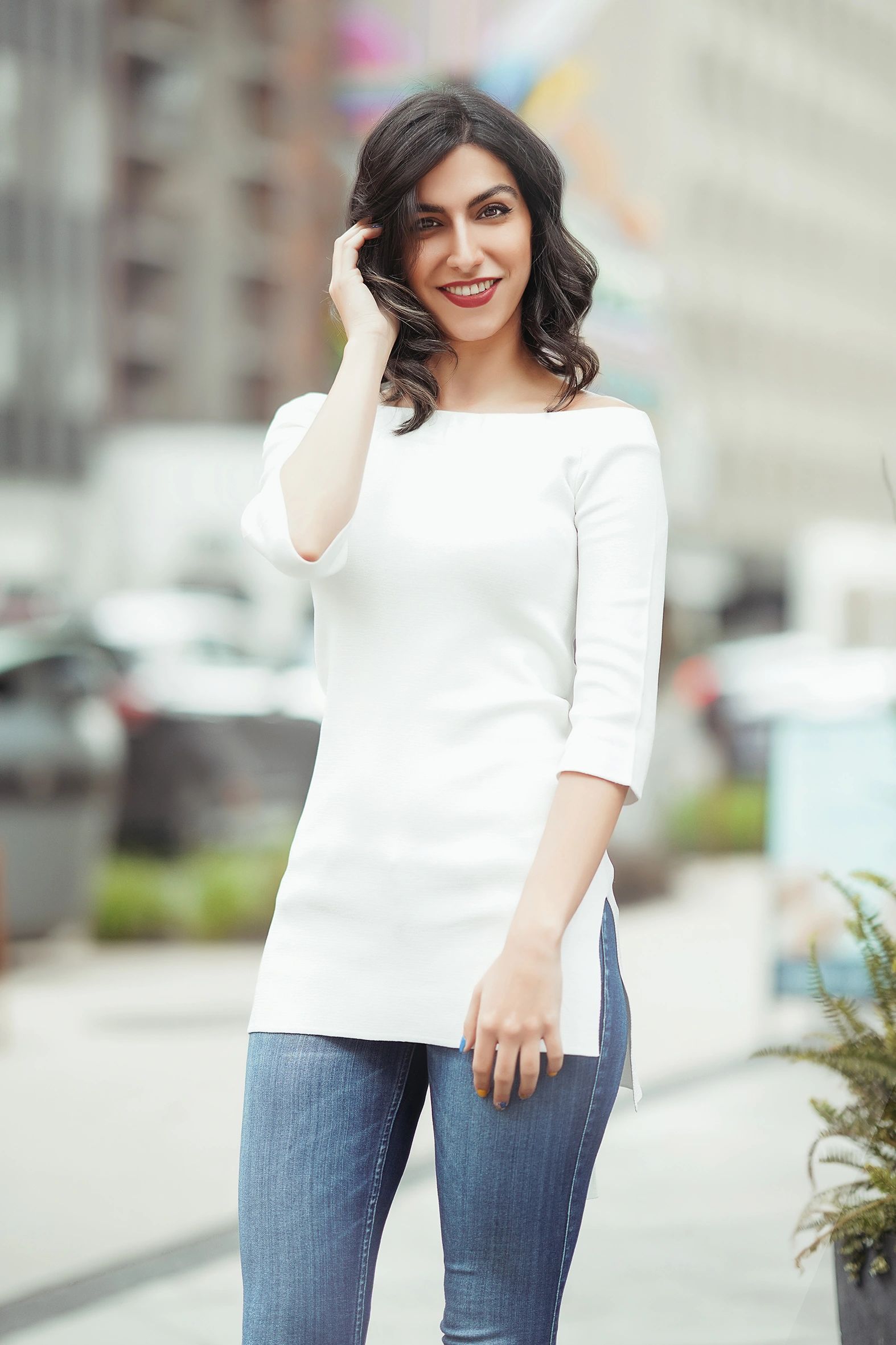 Smiling woman in a white top and jeans posing outdoors. Cinematic color light portrait photography b