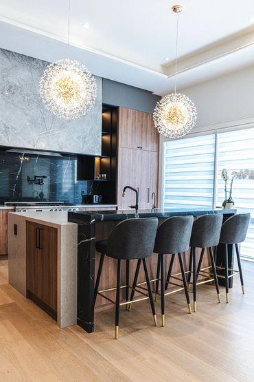 Modern kitchen with elegant lighting and stylish bar stools around a marble island.