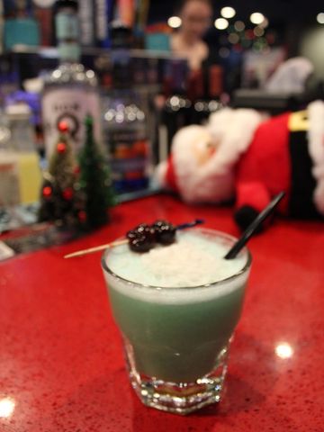 Festive cocktail with a cherry garnish on a red bar counter.