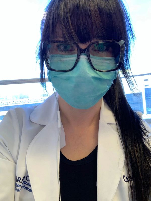 Catherine working as a nurse in lab coat and mask.
