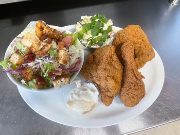 Plate with fried chicken, salad, coleslaw, and a side of sauce.