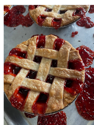 Two freshly baked cherry pies with lattice crusts and spilled filling.