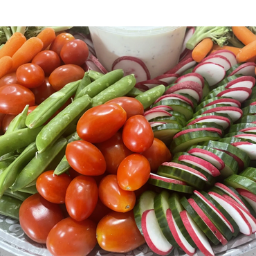 Fresh vegetable platter with tomatoes, snap peas, radishes, cucumbers, and dip.