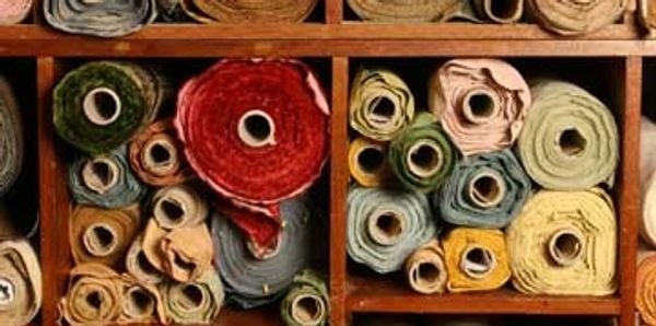 Different colored rolls of fabric stored in a cubed wooden storage shelf.