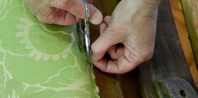 Craftsman cutting a narrow strip of upholstery fabric.