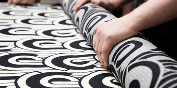 Rolling out black and white fabric on a cutting table.