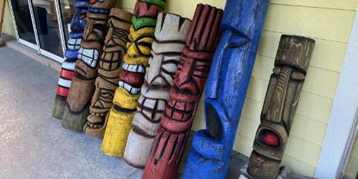 Seven hand-carved wooden tikis in a variety of colors.