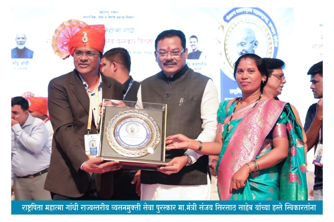 Three people receiving a framed award on stage.