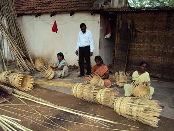 People weaving bamboo baskets outdoors.