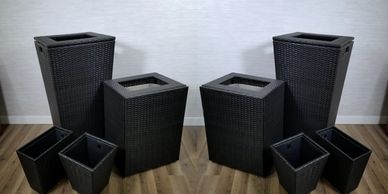 Set of black wicker flower pots of different sizes.