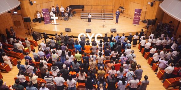 Audience attending a live event in an auditorium with speakers on stage.