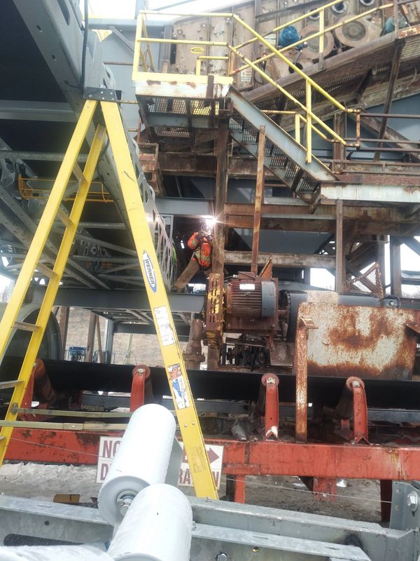 welding out the installation of a new conveyor under an aggregate screening deck