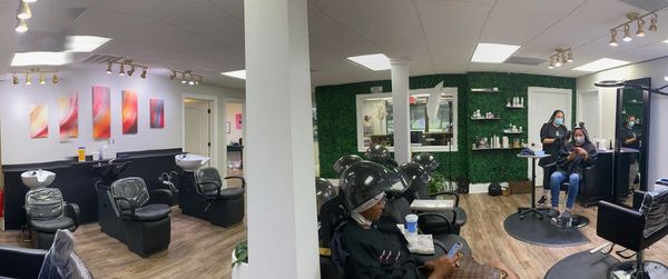 Panoramic view of salon's interior featuring shampoo  bowls and stylists' work areas