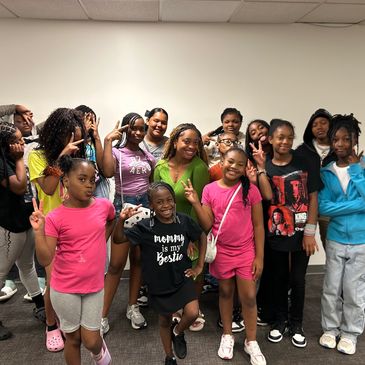 A group of smiling kids and teenagers posing indoors, many showing peace signs.