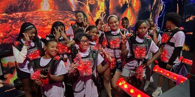 Group of young people posing with laser tag gear in a vibrant arena.