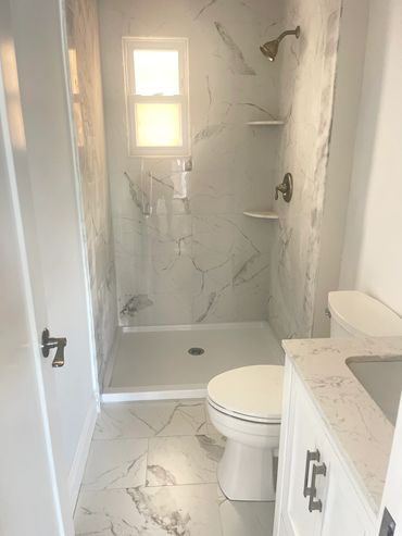 Bright bathroom with marble tiles and a walk-in shower.