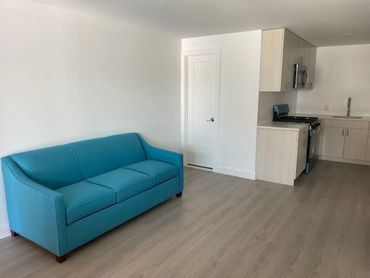 Modern studio apartment with blue sofa and compact kitchen.