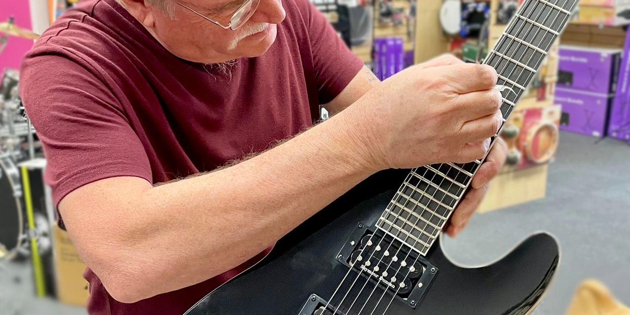 Guitar technician repairing and working on an electric guitar at Mad Music.