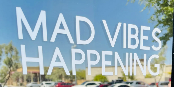 Mad Vibes Happening decal on window in front of store.