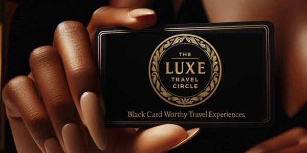 Hand with beige nails holds black 'Luxe Travel Circle' card with gold crest. Dark background