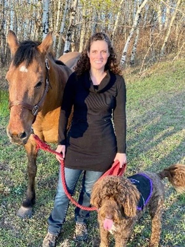 Image of a person with a horse to her left and a dog to her right