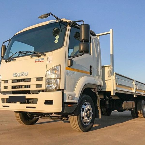 White Isuzu flatbed truck parked on concrete under clear blue sky.