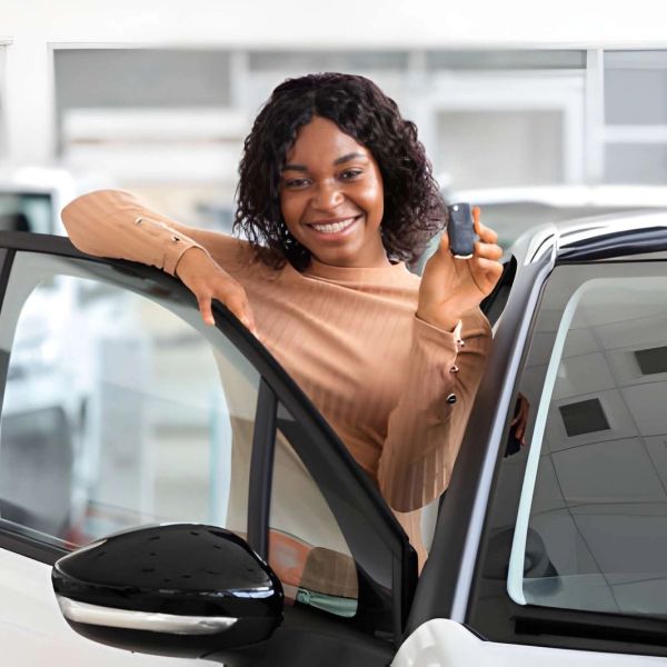 Smiling woman holding car keys beside an open car door.