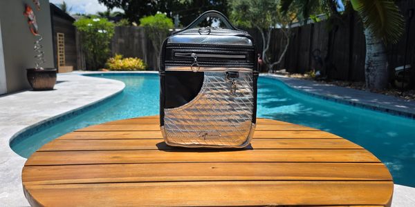 A stylish backpack on a wooden table by a backyard pool.