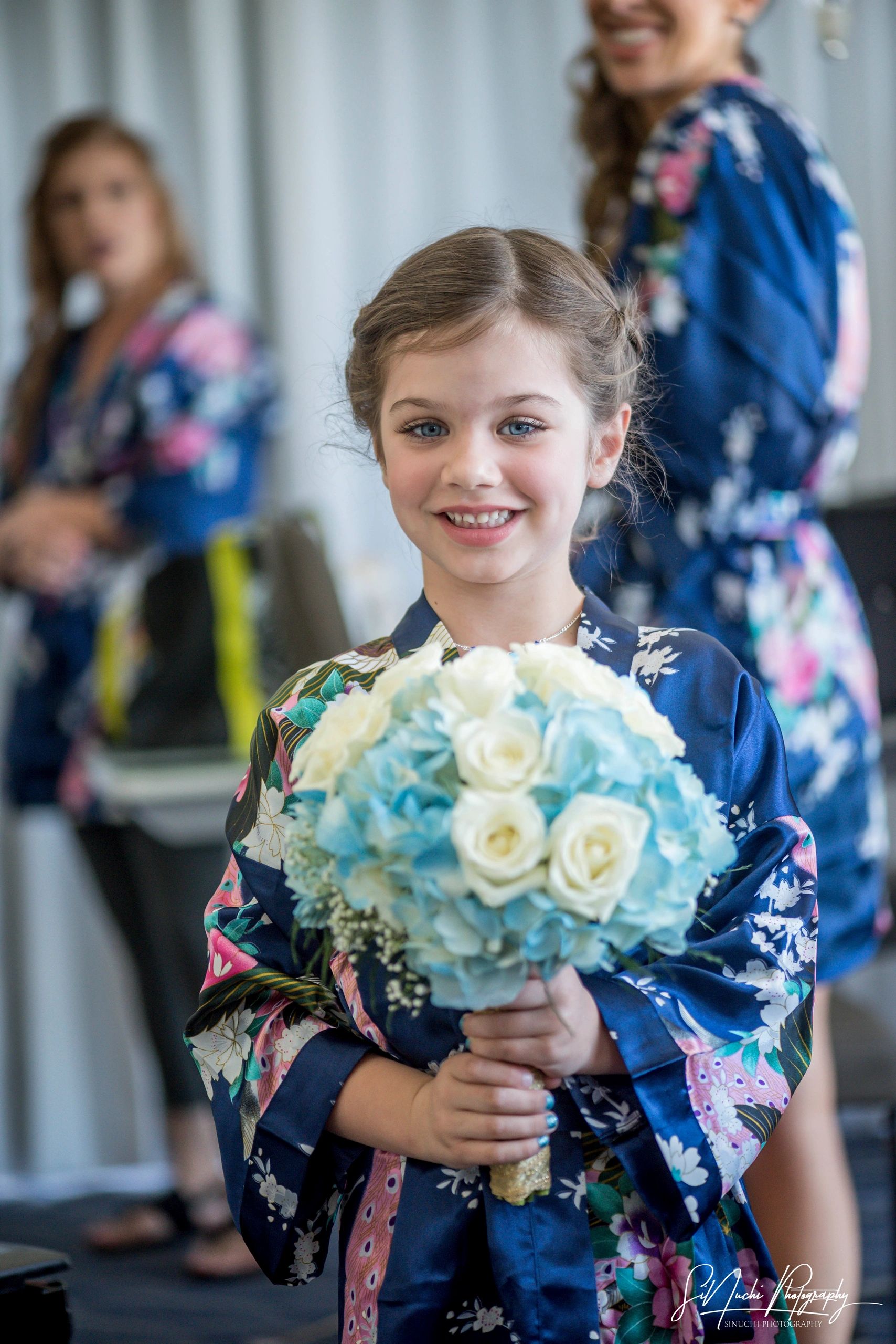 Niña sonriente con ramo de flores en kimono azul.