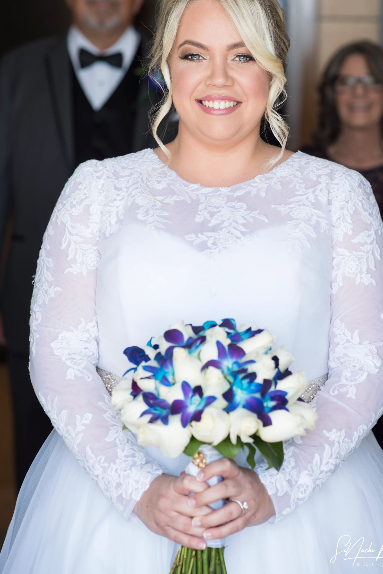 Novia sonriente con ramo de flores blancas y azules.