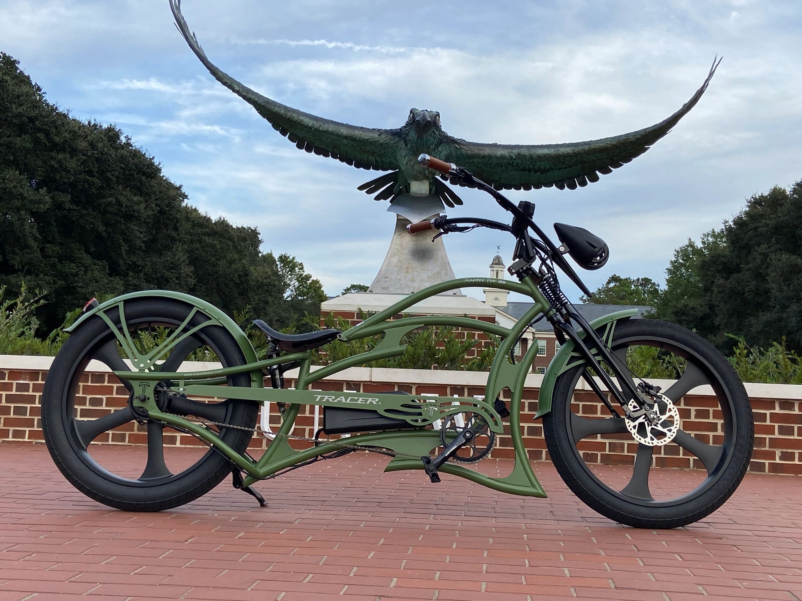 Custom green cruiser bike parked in front of a large eagle statue.