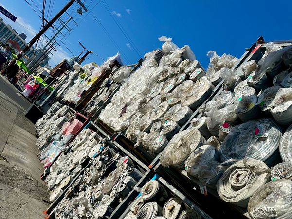 Outdoor racks filled with large rolls of fabric under a clear blue sky.