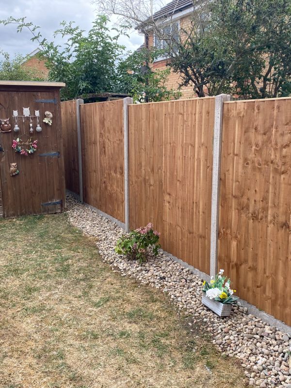 Wooden fence and shed in a garden with decorative items.