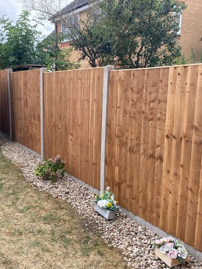 Wooden garden fence with pebbles and flower pots.